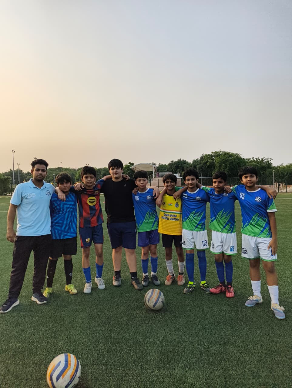 Coach and young footballers on the turf at sunset