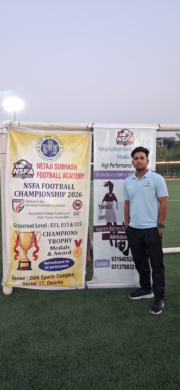Coach beside the championship banner at DDA Sports Complex, Dwarka